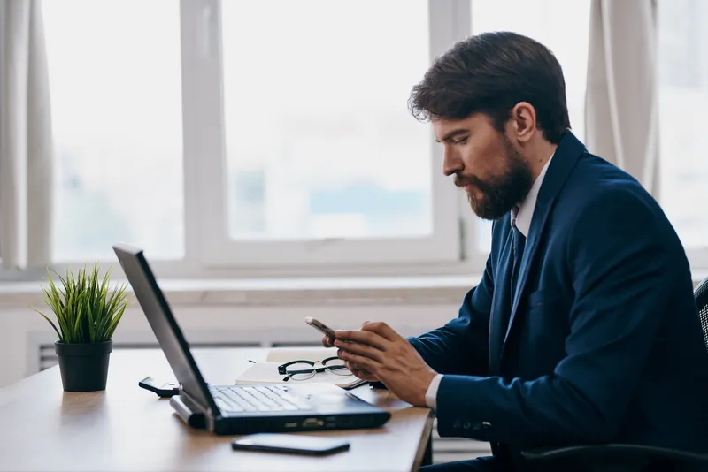 Мужчина работает за ноутбуком, сидя перед ним, технологии, успех