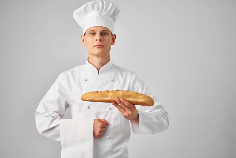 Мужчина в форме повара, пекарь с батоном в руках, свежий продукт