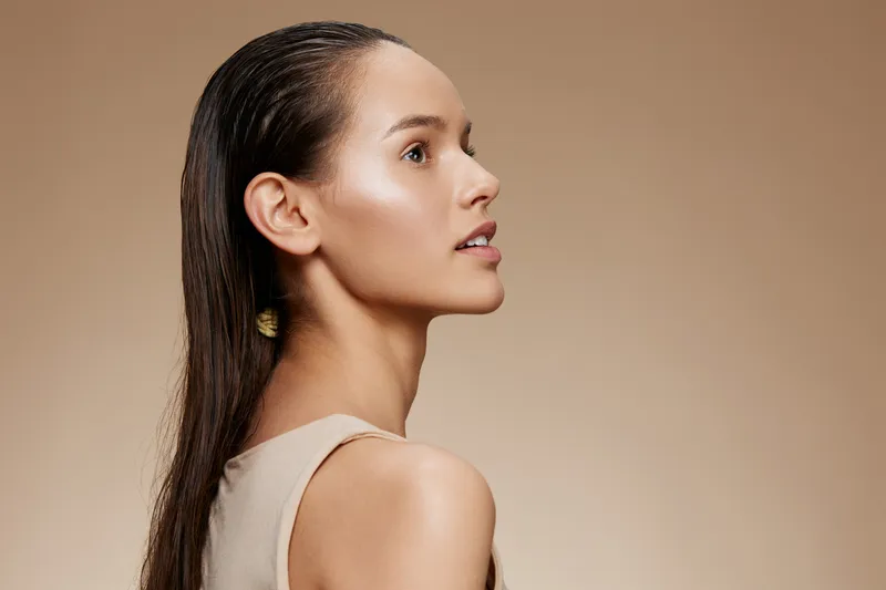 Elegant profile portrait of a young woman with wet hair, showcasing natural beauty and simplicity against a soft beige background Ideal for beauty and wellness themes