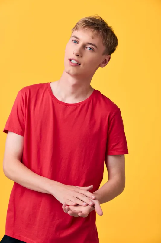 Red shirt worn by a young man against a bright yellow background, casual pose, relaxed expression, clean fashion and lifestyle vibe suitable for advertising, commerce, or social media visuals