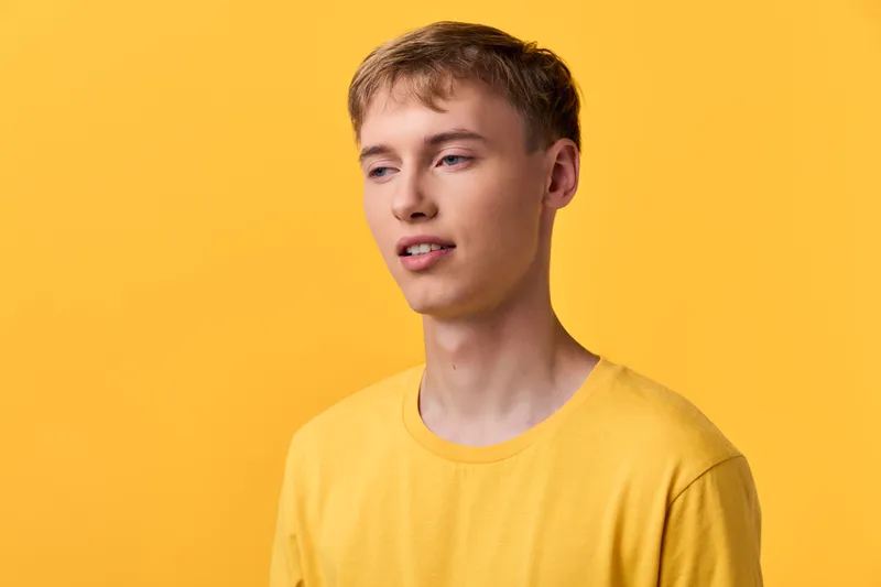 Young man in a bright yellow shirt against a vivid yellow backdrop, casual pose and clean lighting, lifestyle fashion vibe, minimal background, expressive look for branding, product or apparel use