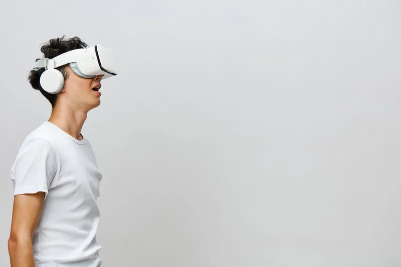 Молодой человек, погруженный в опыт виртуальной реальности, в стильной VR-гарнитуре и наушниках