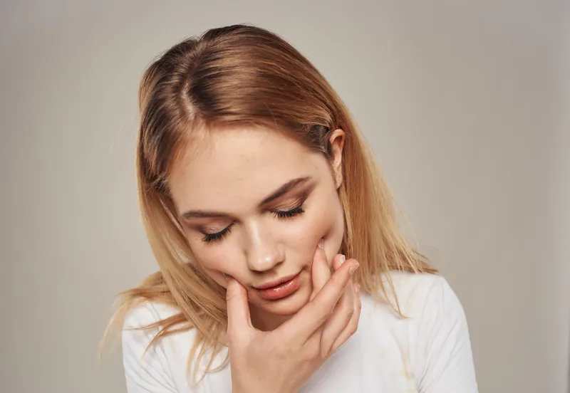Портрет очаровательной женщины с светлыми волосами на сером фоне, крупным планом
