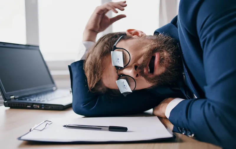 Бизнесмен, спящий на работе, в очках, с листами бумаги