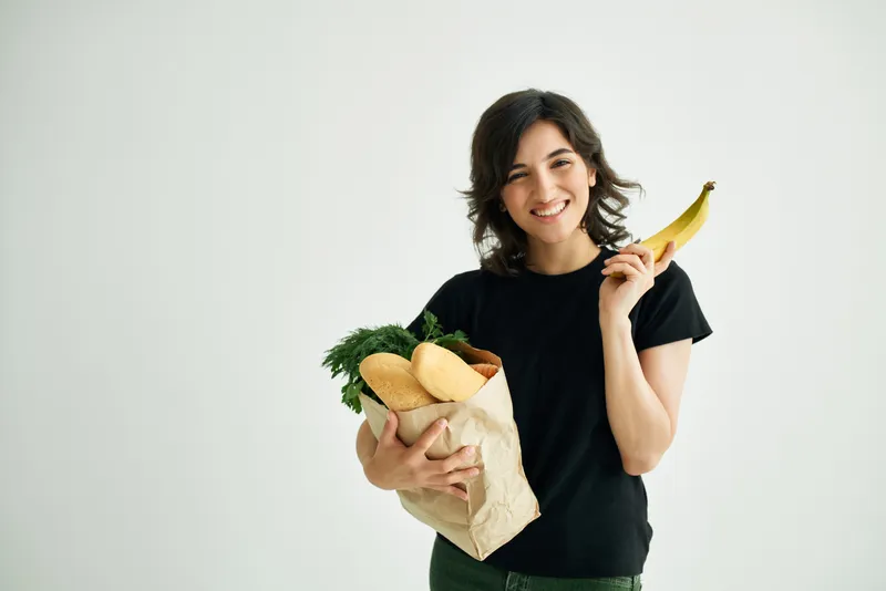 Женщина с пакетом продуктов для доставки занимается приготовлением еды