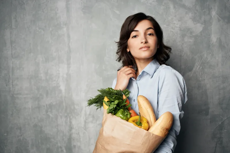 Женщина в голубой рубашке с пакетом продуктов из супермаркета, доставка овощей