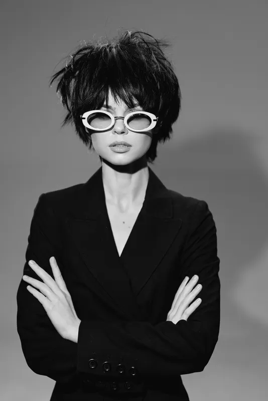 Black and white woman with short hair wearing stylish sunglasses and a dark jacket posing confidently