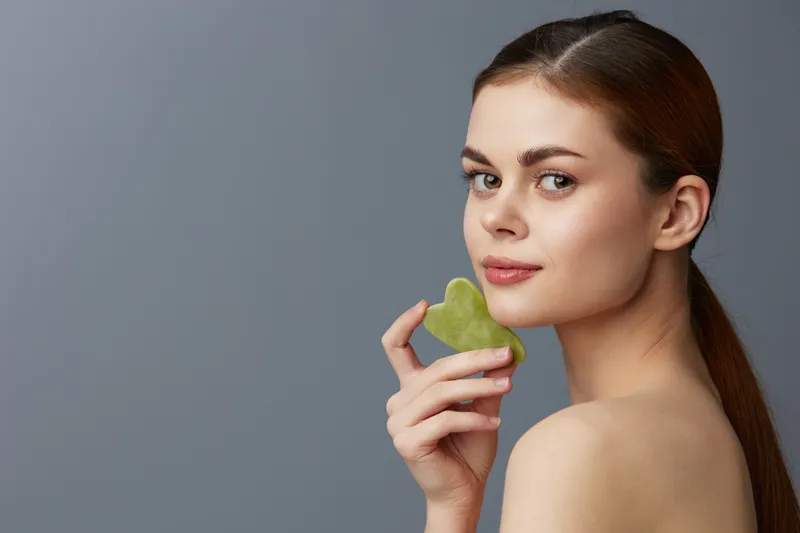 Портрет женщины с facial scraper для ухода за кожей