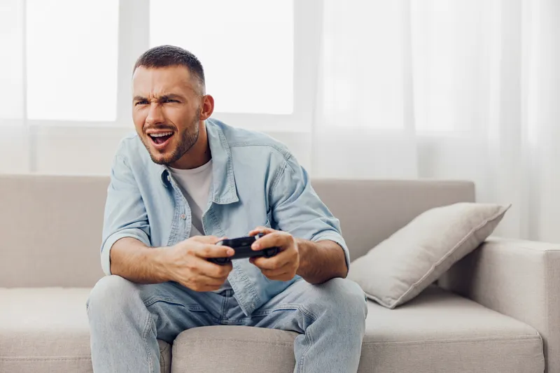 A man playing video games, showcasing emotional intensity in a cozy living room setting, reflecting the themes of solo living and men's mental health.