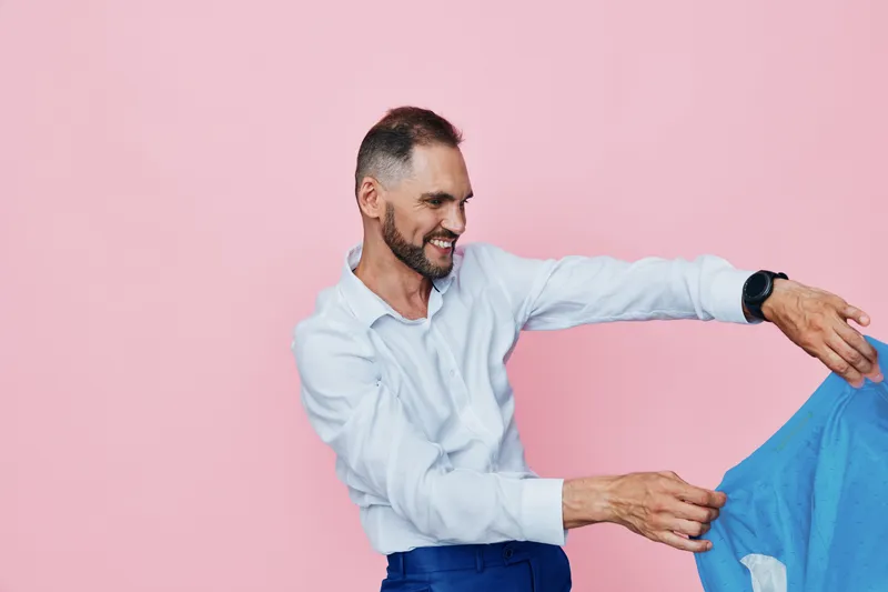 A professional man in business attire smiles warmly against a solid pink background, conveying confidence, approachability, and focus in a modern, isolated studio setting.