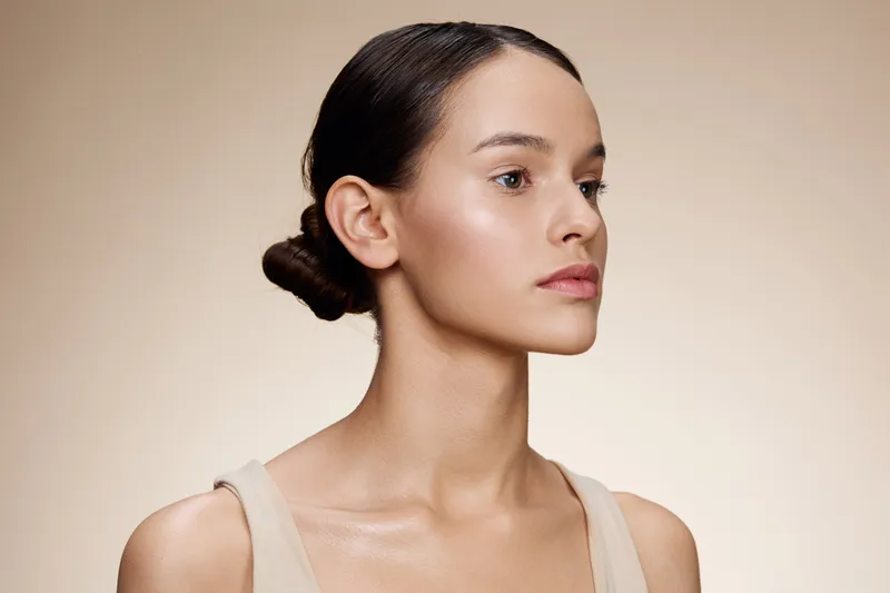 Portrait of a young woman with a smooth complexion showcasing natural beauty, beauty trends, and minimalistic style against a soft beige background