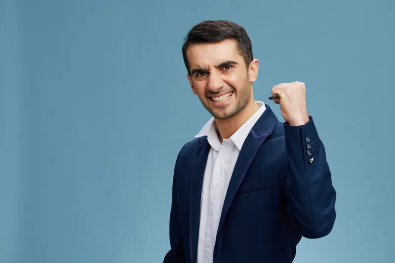 Мужчина с сердитым взглядом, сжимающий ручку в кулаке, позирует, излучая уверенность в себе, на изолированном фоне