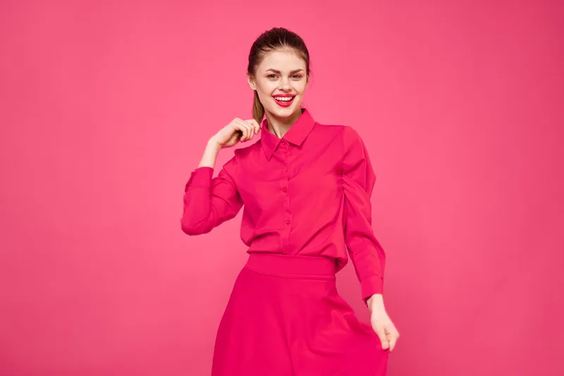 Портрет рыжеволосой женщины в яркой одежде на розовом фоне, обрезанный вид, она жестикулирует руками