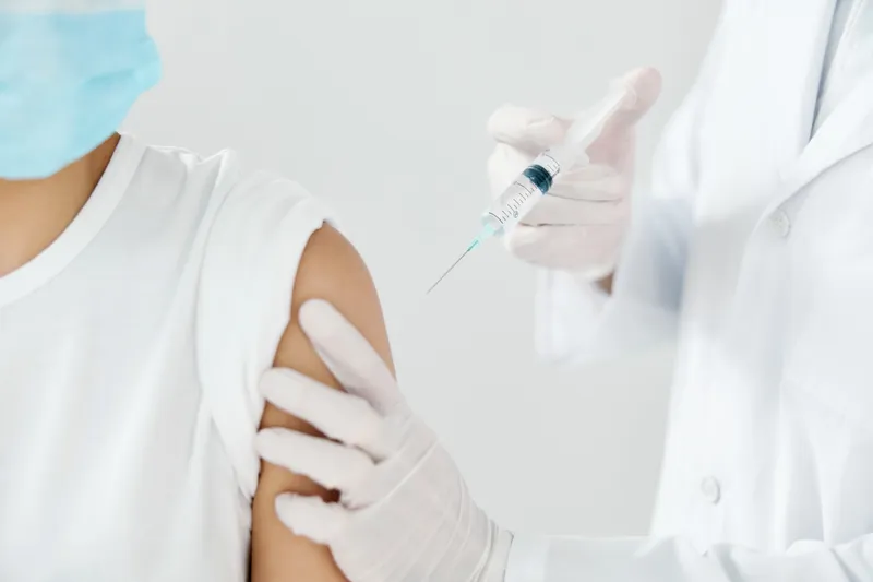 Врач и пациент в медицинских масках, процедура вакцинации от COVID-19