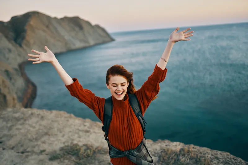 Женщина на фоне осеннего пейзажа: горы, море, пляж