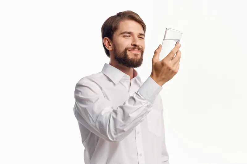 Бородатый мужчина заботится о здоровье, чистая вода, светлый фон
