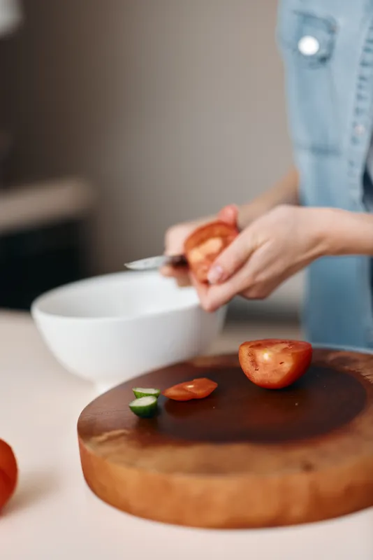 Вкусная домашняя еда: шеф-повар-женщина со свежими ингредиентами на красной кухне готовит аппетитное овощное блюдо на столе