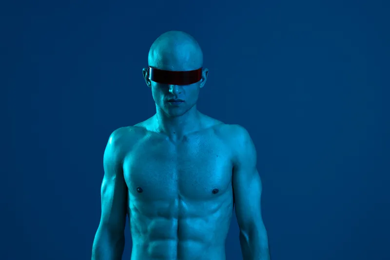 Powerful man in futuristic sunglasses with blue lighting, showcasing a striking look. The image conveys a sense of strength and modernity in a dynamic atmosphere.