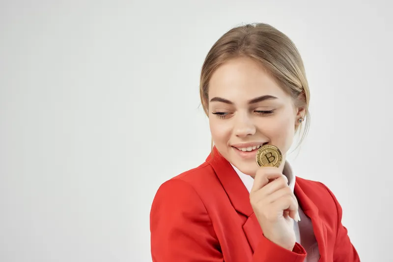 Финансист в красном пиджаке держит золотую монету Bitcoin на изолированном фоне