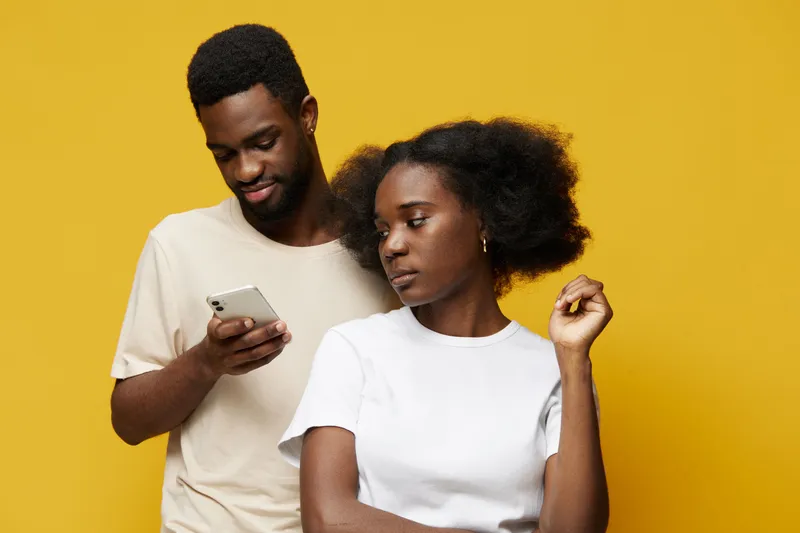 Young African couple with stylish hair posing against a bright yellow background, showcasing modern fashion and emotional connection in casual attire