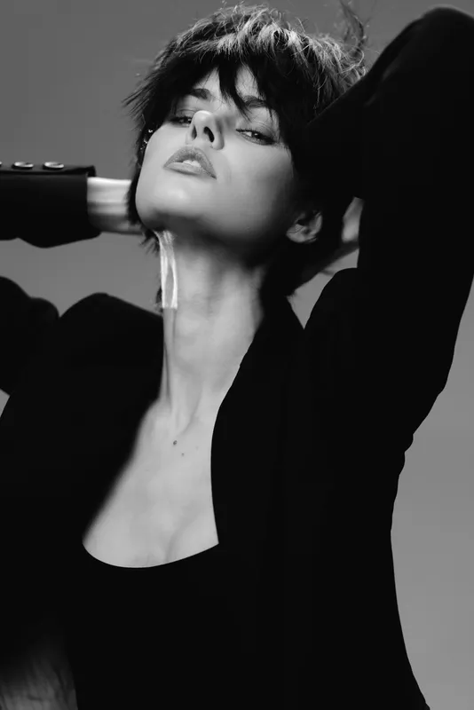 Black and white portrait of a stylish woman with short hair and confident expression, wearing a dark jacket.