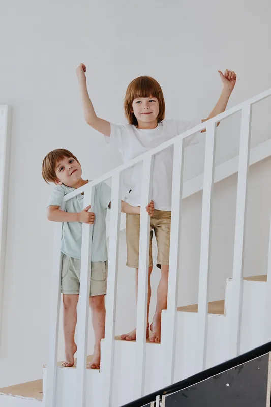 Happy children playing on stairs, enjoying their carefree childhood and expressing joy and excitement in a bright, welcoming home environment.