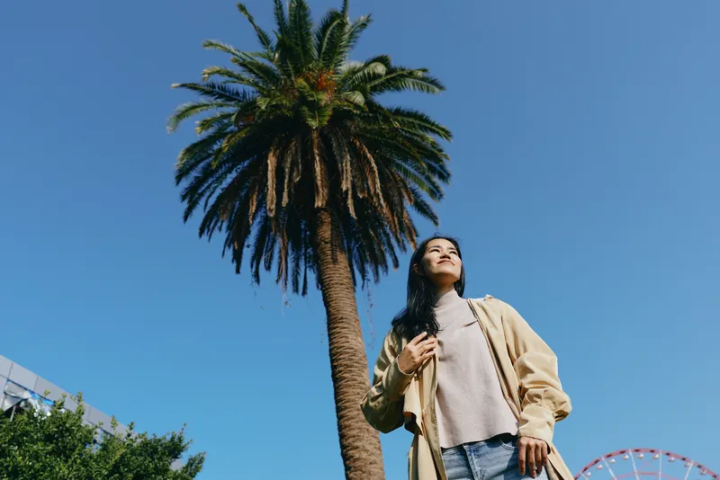 Palm, outdoor, woman, casual, sunny, sky, park, breeze, leisure, travel, scenery, sunlight, nature, summer, urban, street, pose, fashion, denim, cardigan, sneakers, confidence, expression, horizon,
