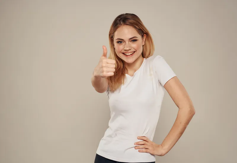 Счастливая женщина жестикулирует, указывая пальцем в сторону, и демонстрирует эмоции