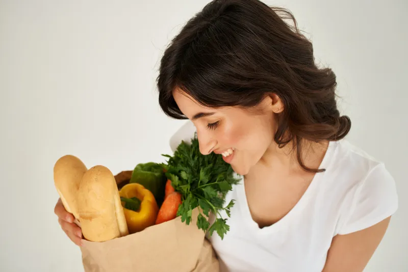 Брюнетка в белой футболке с пакетом продуктов для доставки здоровой пищи, крупный план