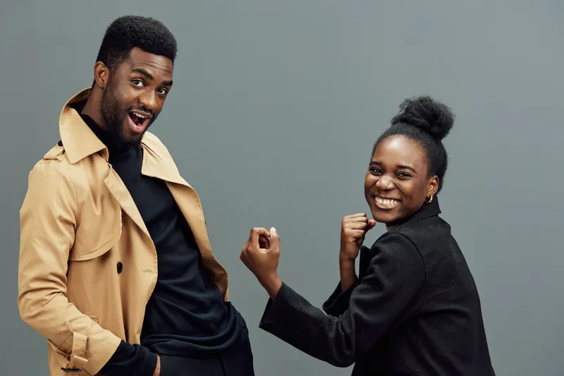 Happy diverse models celebrating success in stylish outfits against a gray background, showcasing joy and enthusiasm in a modern setting