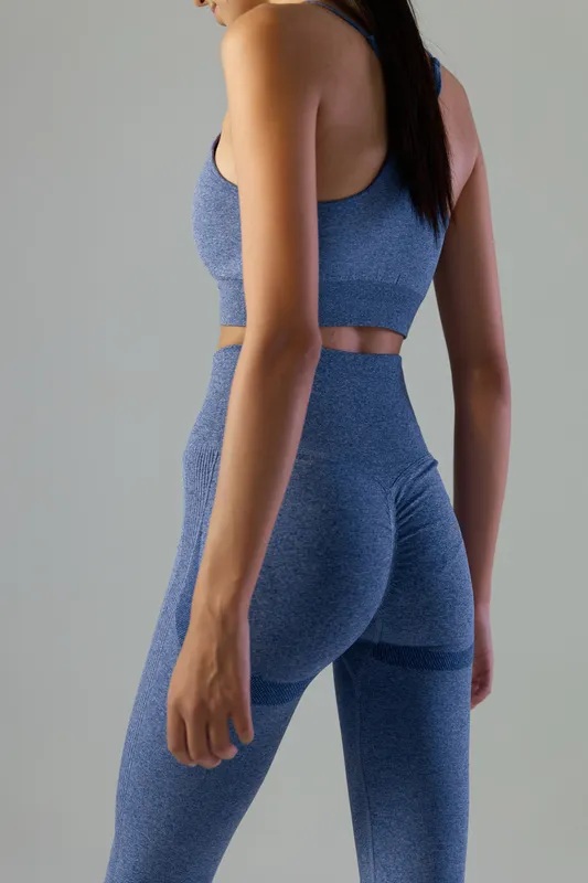 Woman sport fitness wearing blue seamless activewear suit, showing toned body in a minimal studio background, focus on health and workout lifestyle, side view
