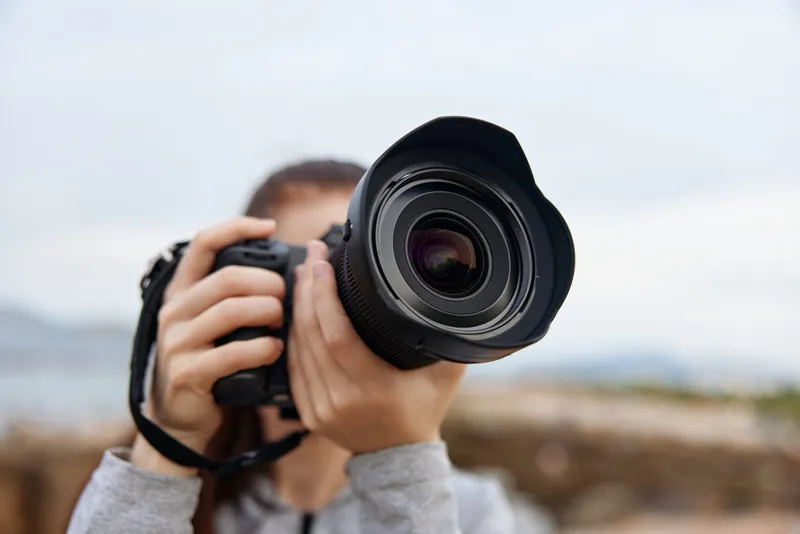 Female photographer with a camera, showcasing passion for photography outdoors, warm colors, nature backdrop, captured emotions, sunset ambiance