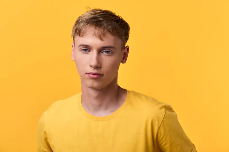Man in a yellow shirt against a bright yellow studio background, showcasing casual fashion, clean lighting and a relaxed expression for lifestyle and product styling