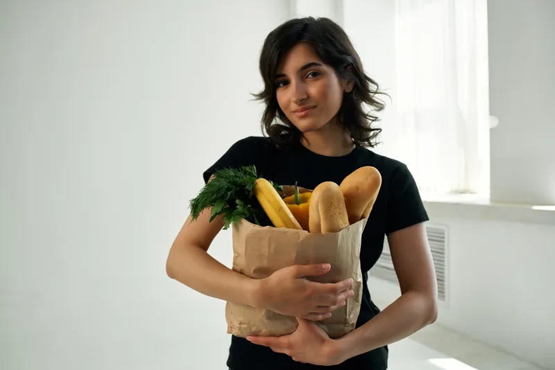 Милая брюнетка дома с пакетом продуктов из супермаркета — здоровое питание