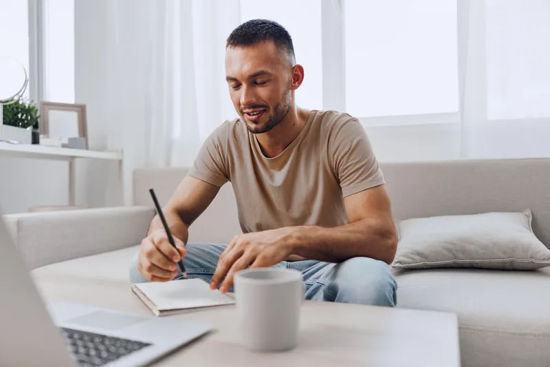 Engaged man writing notes at home workspace, showcasing creativity and productivity in a modern setting. A warm and inviting atmosphere enhances focus and inspiration.