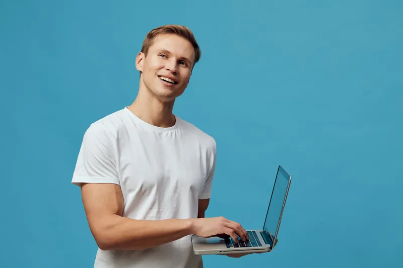 Smiling young caucasian man hold laptop work digital nomad casual wear blue background technology concept