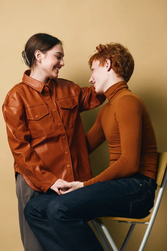 Couple, love, and smile with casual clothes indoors for relationship, support, and connection between woman and man in warm colors on beige background.
