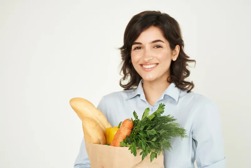 Улыбающаяся женщина с пакетом продуктов, здоровой пищей, в супермаркете, домохозяйка