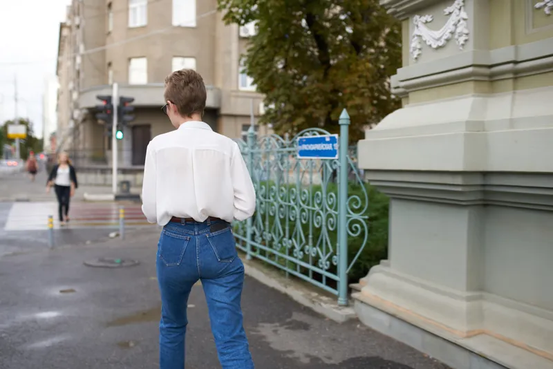 Симпатичная женщина в очках гуляет по городу с книгой в руках