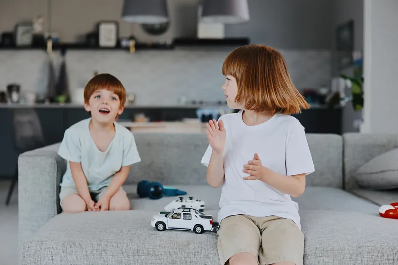 Happy children playing together in a cozy living room, enjoying their time with toys and laughter. A warm and inviting atmosphere surrounds them.
