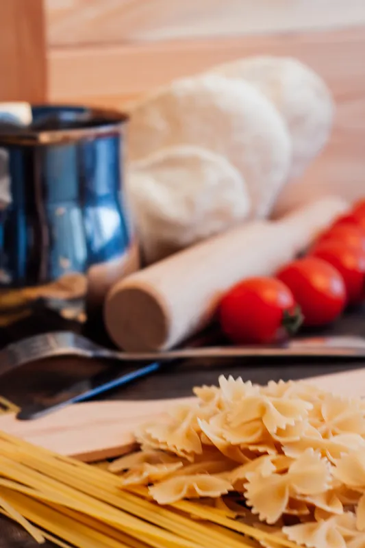 Макароны рассыпаны по столу, помидоры, итальянская кухня