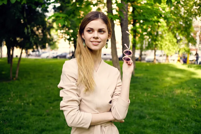 Симпатичная женщина отдыхает на фоне зелёных деревьев в парке