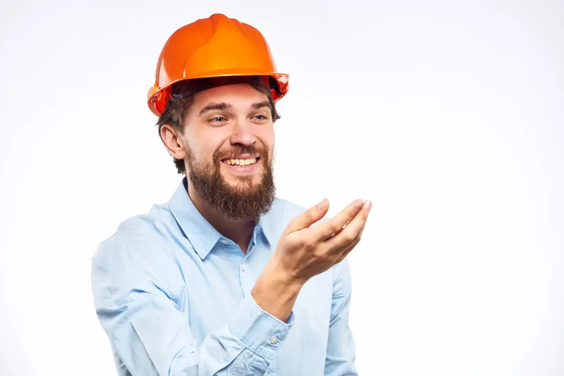 Мужчина в рабочей форме и оранжевой каске жестикулирует руками, проявляя эмоции