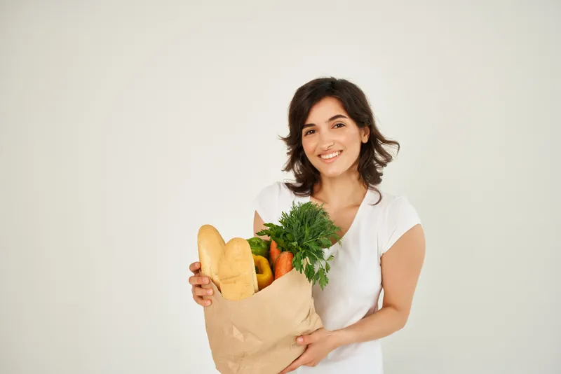 Весёлая брюнетка с пакетом продуктов, доставка здоровой еды