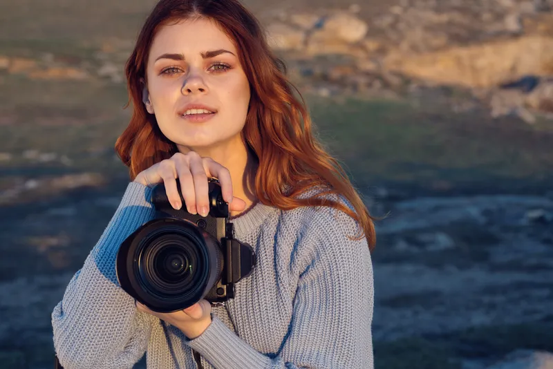 Жизнерадостная женщина-фотограф с камерой на фоне природы, пейзаж, образ жизни