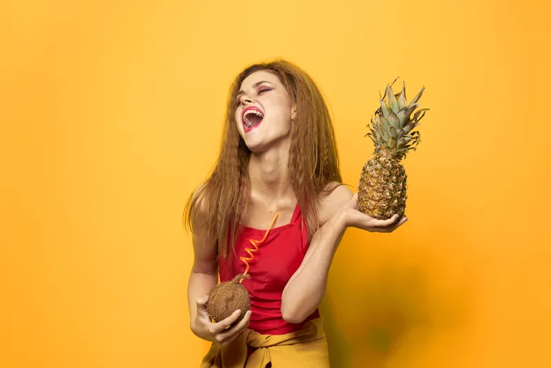 Женщина с ананасом и коктейлем из кокоса, экзотические фрукты, летний образ жизни, желтый фон