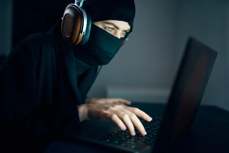 Женщина ночью сидит перед ноутбуком в наушниках, используя интернет-технологии