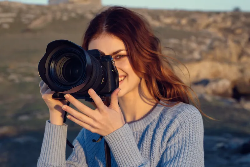 Веселая женщина-фотограф на фоне скалистых гор, пейзаж, отдых на природе