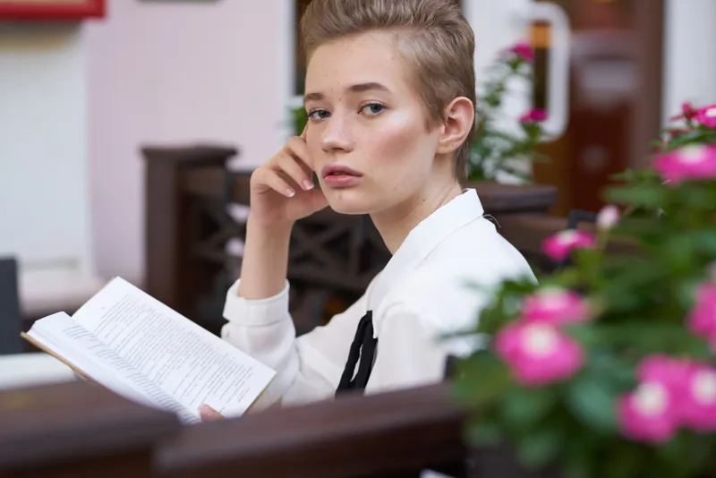 Студент с книгой в руках на улице во время каникул в городе, летнее общение
