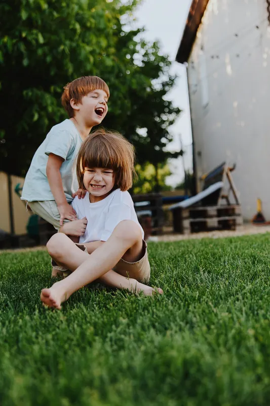Happy children playing outdoors, enjoying a sunny day surrounded by greenery, creating joyful memories in a vibrant backyard environment.
